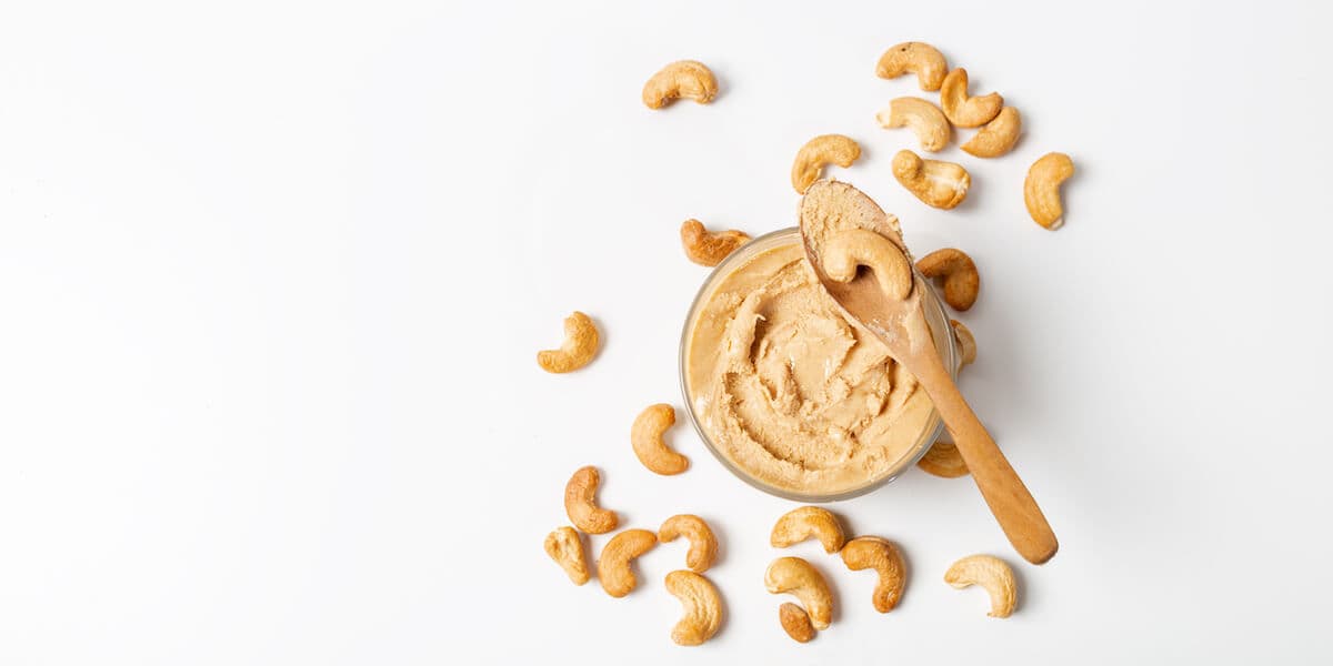 Jar of cashew butter with cashew nuts on the white background