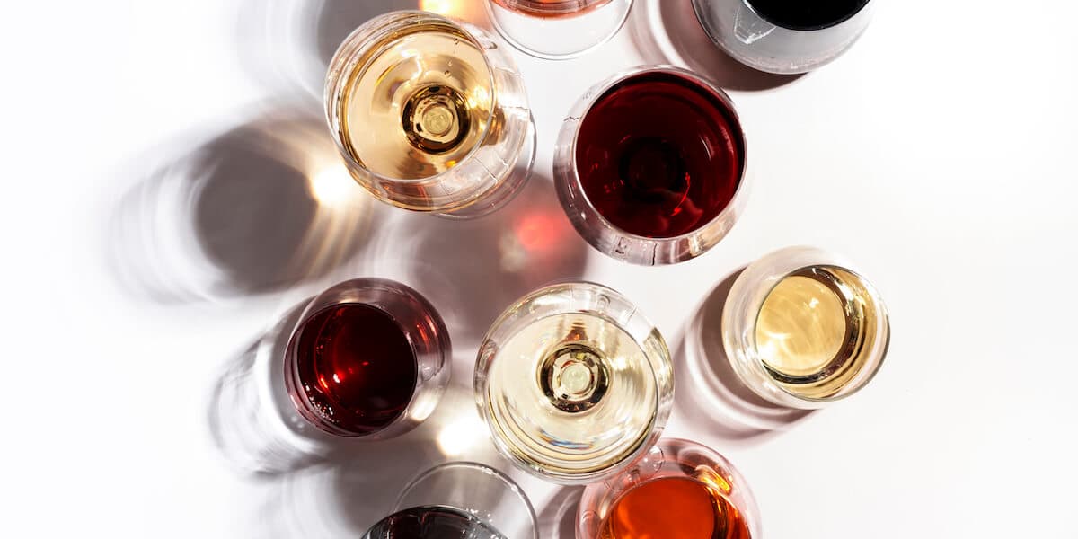 Red, rose and white wine in glasses on white background, top view.
